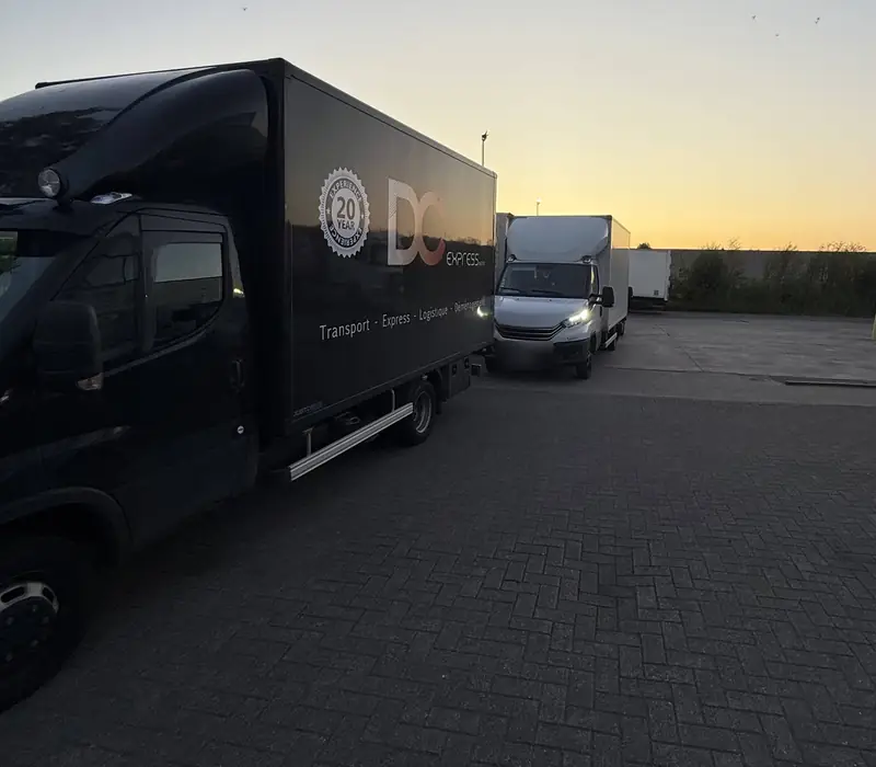 Camion noir DC Express et camionnette au dépôt, au coucher du soleil